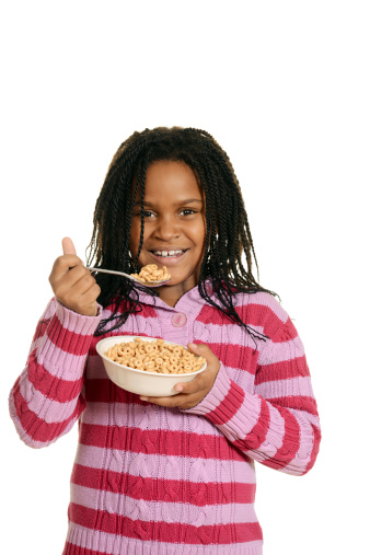 isolated little black girl enjoying bowl of cereal