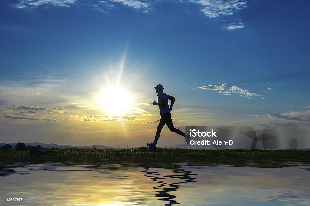 Silhouette man running on meadow over river Silhouette man running on meadow over river, sunrise -sundown sky at background. Runner - sprinter on field Active Lifestyle Stock Photo