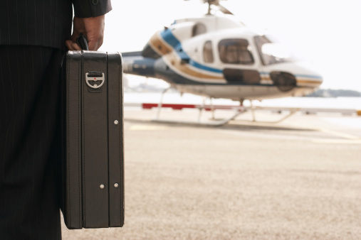 Side view of man holding briefcase standng in front of Helicopter