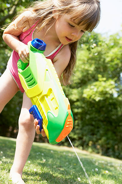 istock Girl Shooting Water Pistol Into The Grass 462411209