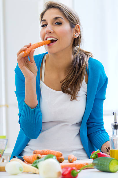 istock Young woman having fun with a carrot in the kitchen 462412303