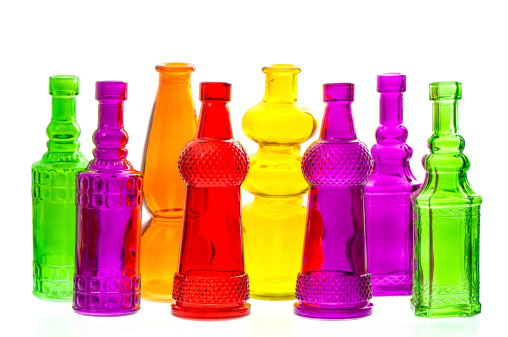 group of colorful empty transparent glass bottles on white background