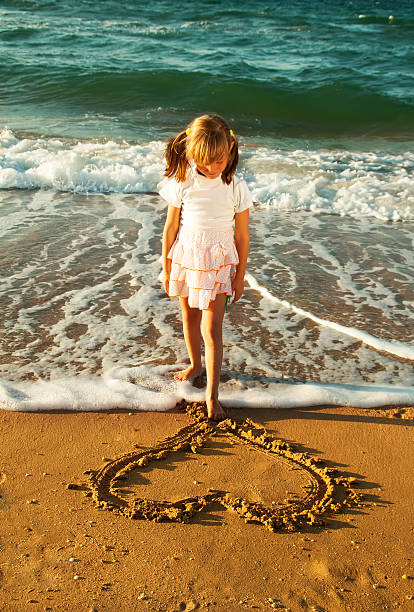 девушка на пляже, рисунок сердца в песке - sandy brown day the americas north america стоковые фото и изображения
