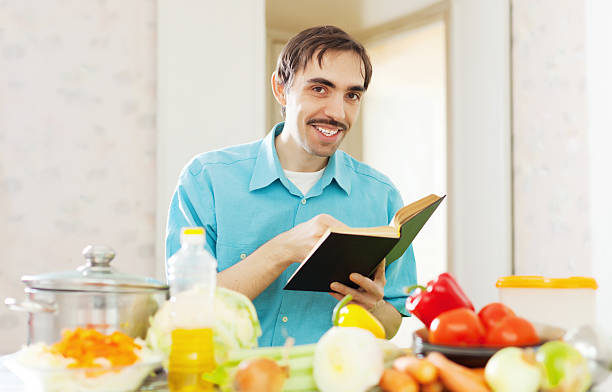 istock cheerful man cooking   with cookbook 462434461