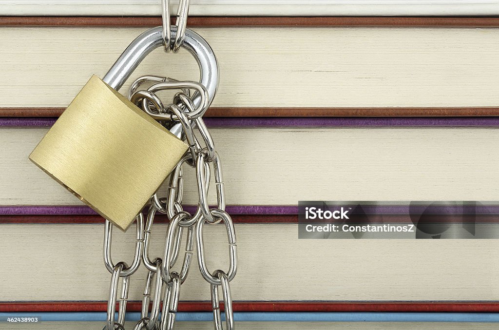 forbidden knowledge padlock with chain against books closeup Accessibility Stock Photo