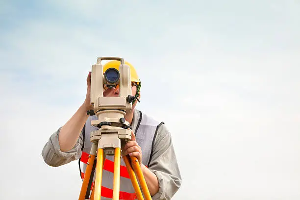 Surveyor engineer making measure with cloud background on outdoor