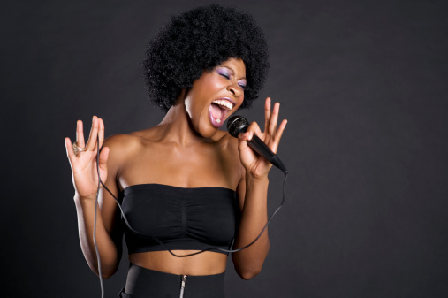 Woman singing on microphone over colored background