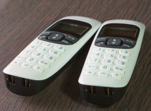 Cordless phones over a dark wooden table, close up