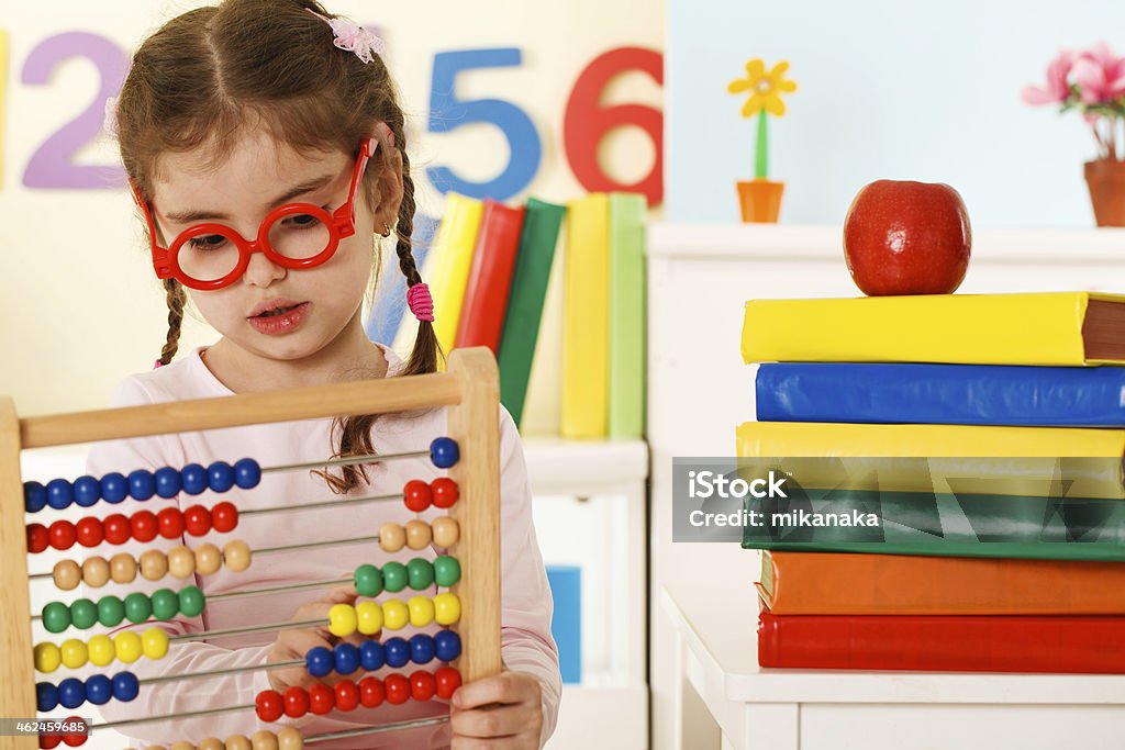 Little girl using an abacus in a colorful school room Little Girl Playing with Colorful Abacus Beads 2-3 Years Stock Photo