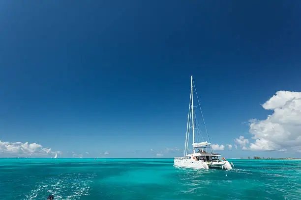Close-up of single catamaran with tall white mast in tropical waters in the British Virgin Islands