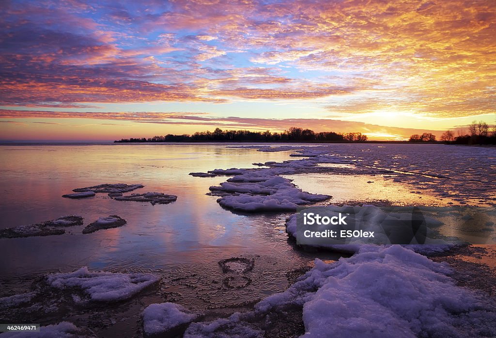 Winter landscape Winter landscape with lake and sunset fiery sky. Composition of nature. Beach Stock Photo