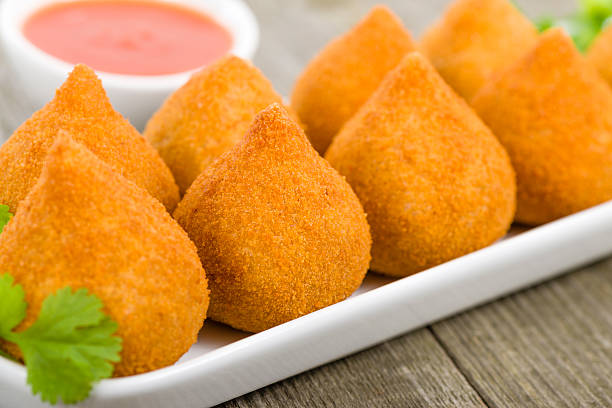 Coxinha de Galinha on a wooden table with sauce Coxinha de Galinha - Brazilian deep fried chicken snack, popular at local parties. Served with chili sauce. savory stock pictures, royalty-free photos & images