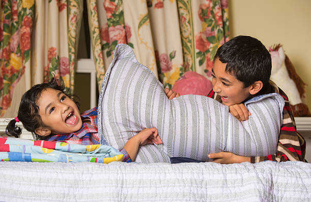 Siblings Enjoying a Pillow Fight stock photo