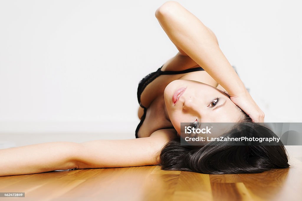 Beautiful appealing young woman Beautiful appealing young woman lying on her back in seductive lingerie looking back at the camera with a serious wide eyed expressiong Adult Stock Photo