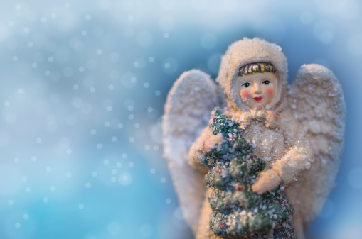 Beautiful angel figurine with Christmas tree and falling snow