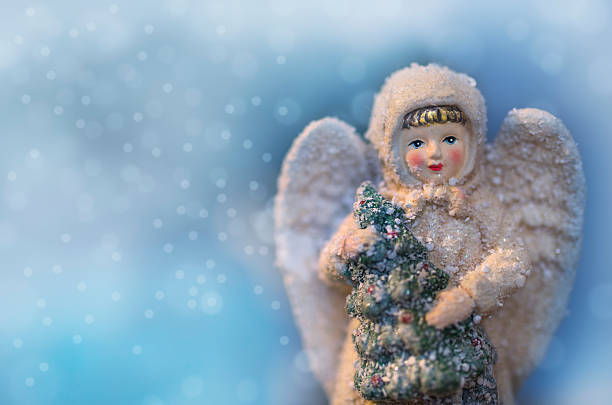 Beautiful angel figurine with Christmas tree and falling snow stock photo