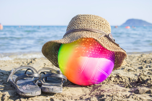 inflatable colorful beach ball and hat on sand and seashell
