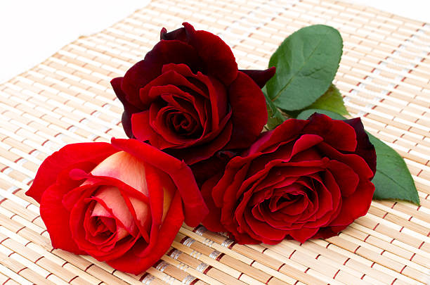 istock three red roses are on a bamboo napkin 462503649