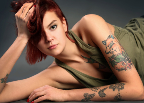 Young tattooed girl on dark background
