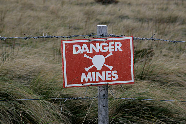 A Danger Mines sign on a barb wire fence Landmines sign, danger minefield in the Falklands land mine stock pictures, royalty-free photos & images