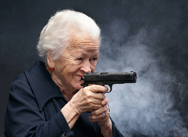 Old woman Old woman with pistol in smoke on a gray background old guns stock pictures, royalty-free photos & images