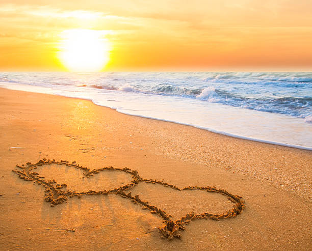 istock Two hearts etched together on sandy beach at susnet 462537525