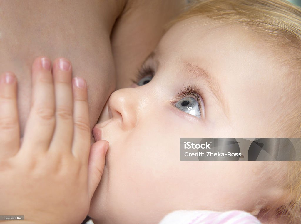 A baby breast feeding on his mother little baby sucking breast mother with open eyes Adult Stock Photo