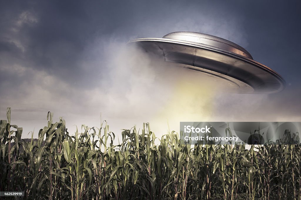 UFO hovering over a crop field UFO over a crop field on a dark sky Aggression Stock Photo