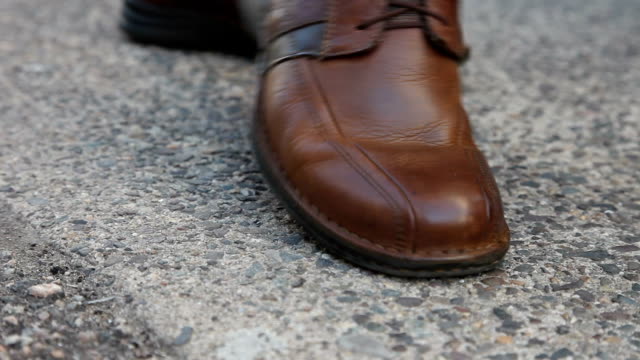 Person walking along crushing a cigarette butt with shoe