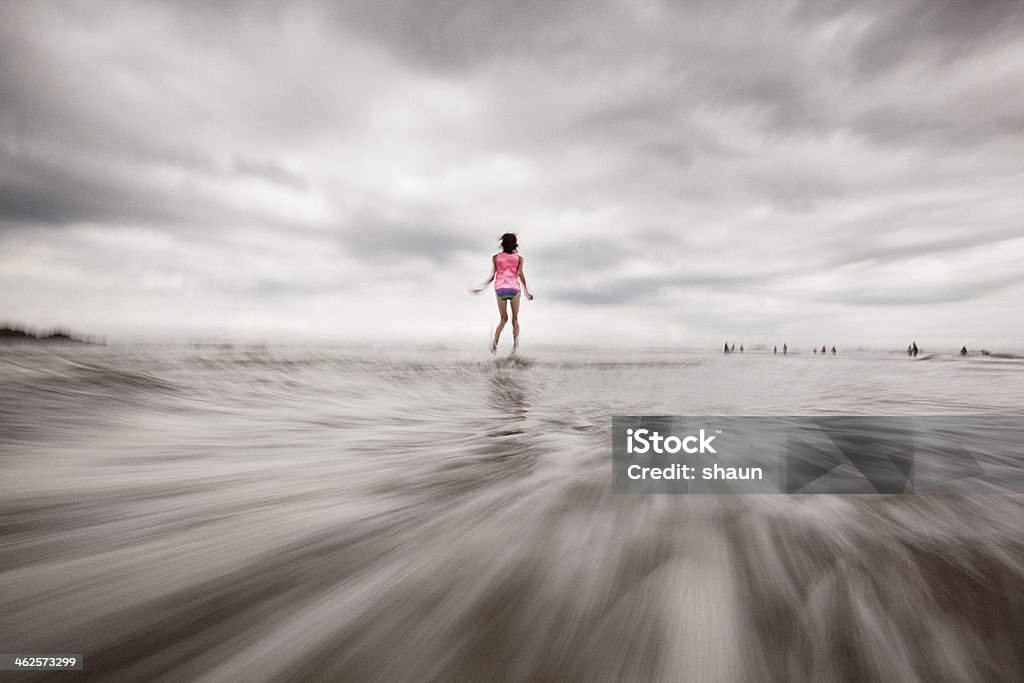 Summer Fun at the Beach A girl jumping in the water at the beach. Blurred Motion Stock Photo