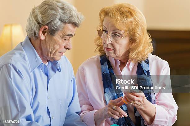 Senior Woman Explaining Prescription Medication Dosage To Husband Stock Photo - Download Image Now