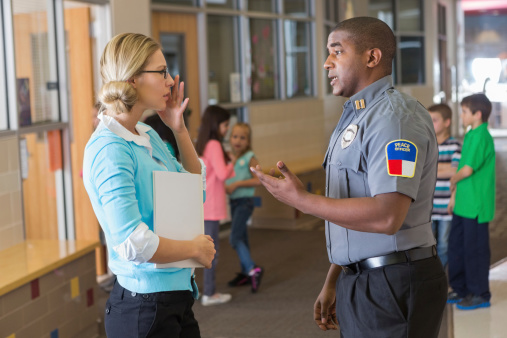 Security or police officer talking with elementary school teacher 