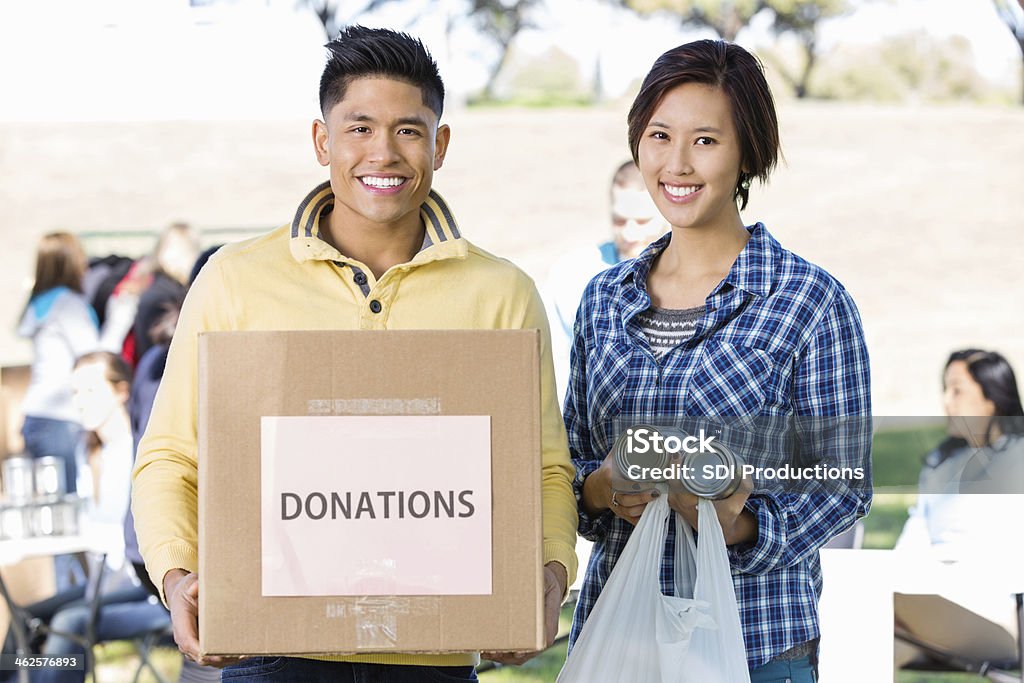 Pareja joven asiática trabajo voluntario para la donación en automóvil al aire libre - Foto de stock de Caja de donaciones libre de derechos