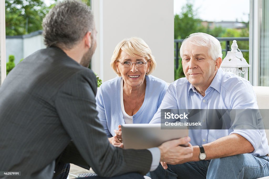 Senior couple talking with financial advisor Senior couple having meeting with financial advisor or insurance agent at home. Senior Couple Stock Photo