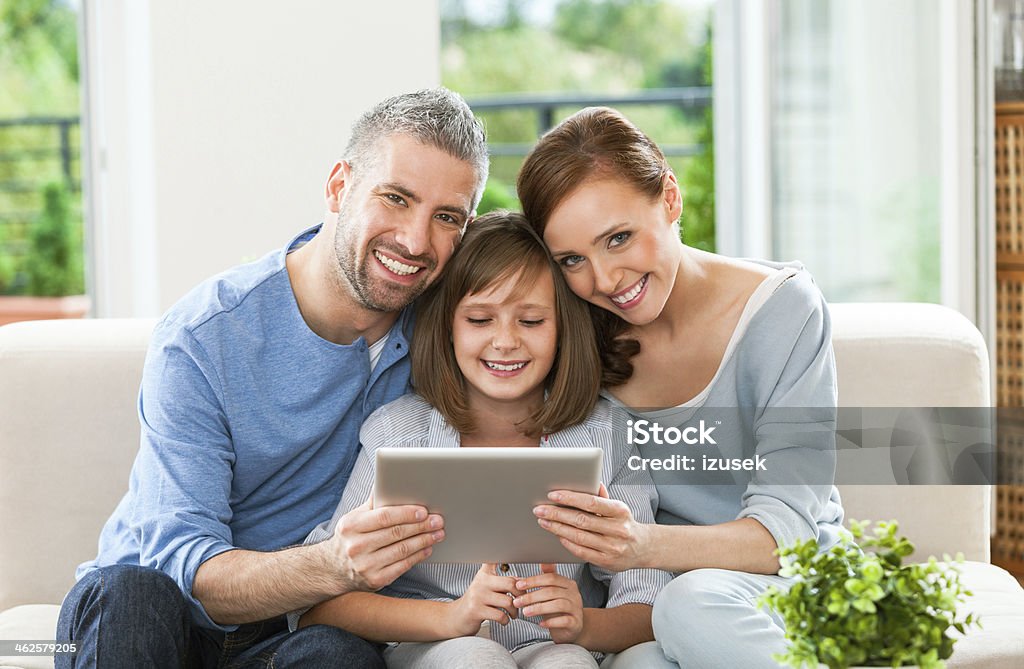 Happy family with digital tablet Happy parents with their daughter using a digital tablet, smiling at the camera. Digital Tablet Stock Photo