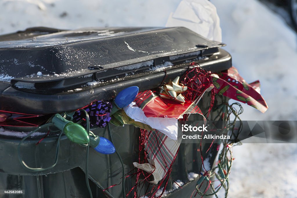 after Christmas trash bin close up a large plastic trashbin overflowing with garbage and discarded Christmas paper lights bows etc Garbage Stock Photo