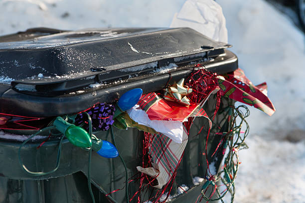 after Christmas trash bin close up a large plastic trashbin overflowing with garbage and discarded Christmas paper lights bows etc christmas chaos stock pictures, royalty-free photos & images