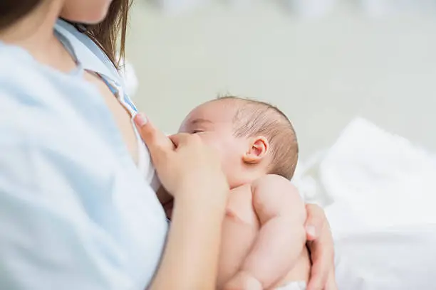 Mother breastfeeding a new born baby boy in a hospital room