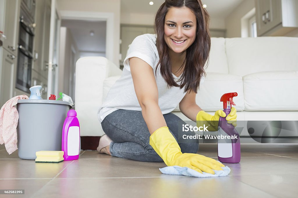 Woman kneeling at the floor cleaning Woman kneeling at the floor cleaning while smiling 20-29 Years Stock Photo