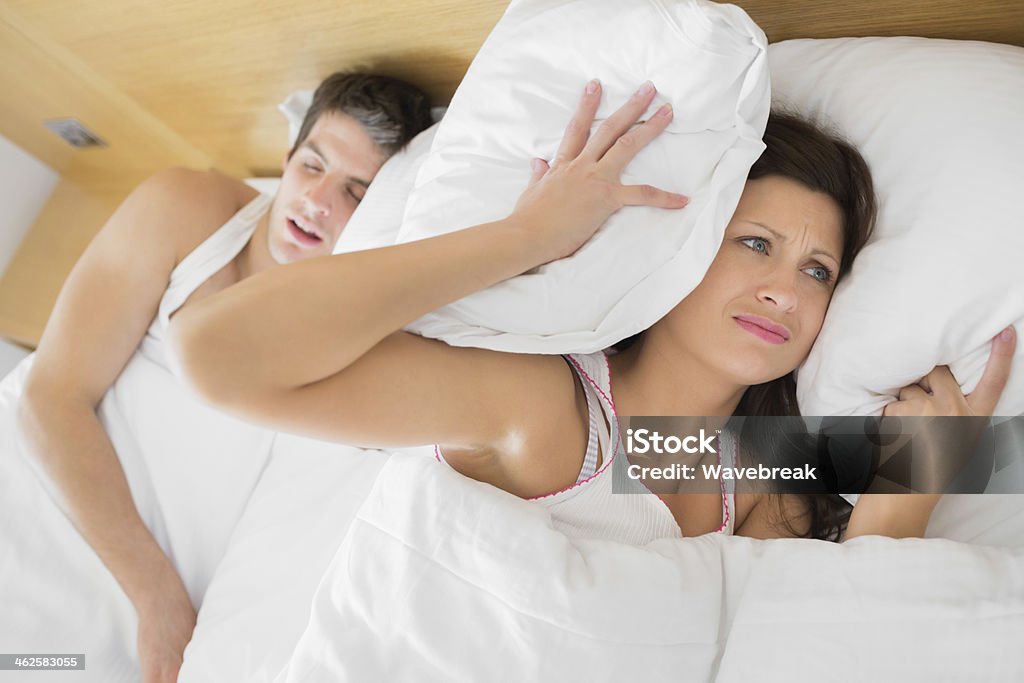 Annoyed woman trying to block out partners snoring Annoyed woman trying to block out partners snoring in hotel room 20-29 Years Stock Photo