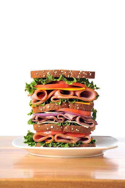 Triple Decker Dagwood Sandwich on Whole Wheat Bread Vertical image of a triple decker dagwood sandwich sitting on a white plate. dagwood stock pictures, royalty-free photos & images