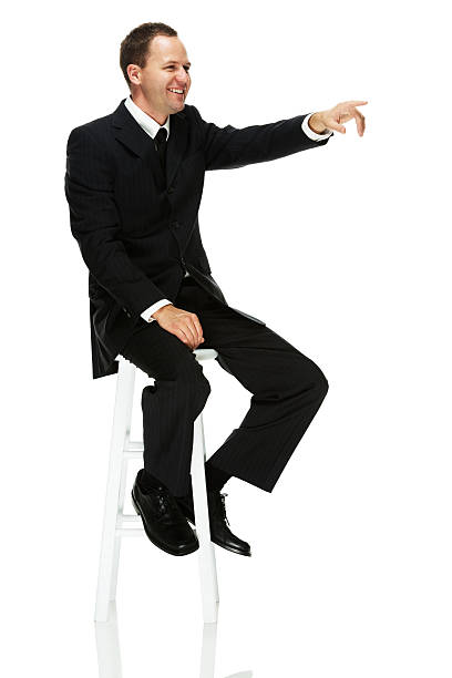 istock Smiling businessman sitting on stool and pointing 462587273
