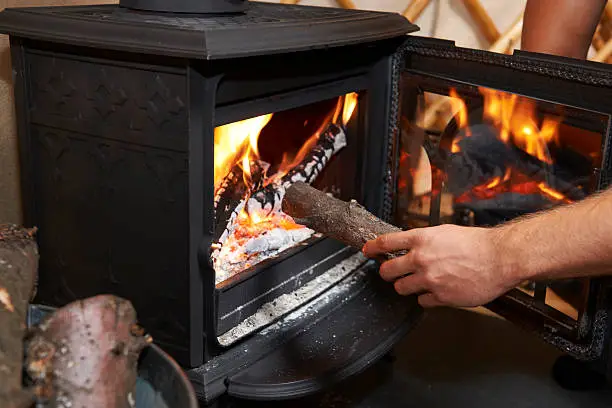 Photo of Man Putting Log Onto Wood Burning Stove