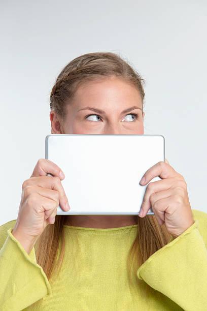 istock Young Woman looking from behind Digital Tablet 462600057
