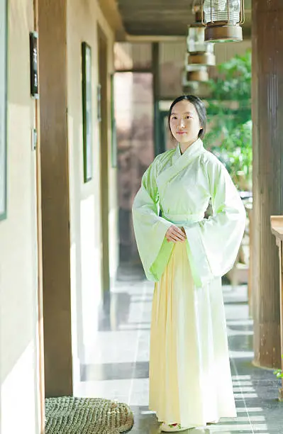 Happy east asian teenage girl dress in Hanfu (traditional Chinese clothing) opening the wooden window