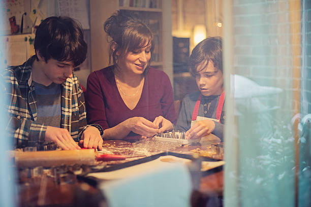 madre e hijos la galleta de jengibre en su casa a través de la ventana. - christmas child cookie table fotografías e imágenes de stock