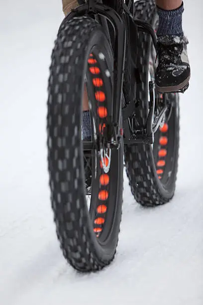 Action shot of a fatbike focusing on how big the tires are. The orange circles are portions of the rims that have been cut out to reduce the weight of the rims.