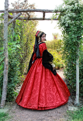 Photo of a young woman in a garden wearing a French hood with an early 16th Century \