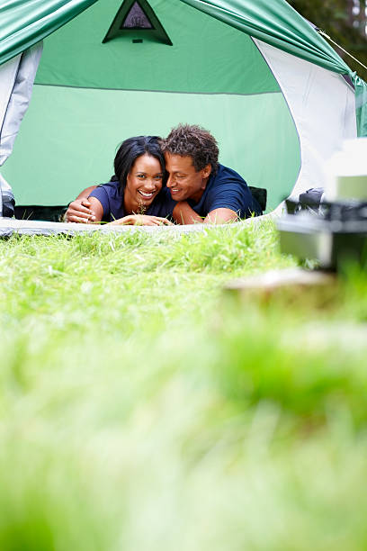 Mixed race couple camping outdoors Mixed race couple lying together in camping tent smiling women lying down grass wood stock pictures, royalty-free photos & images