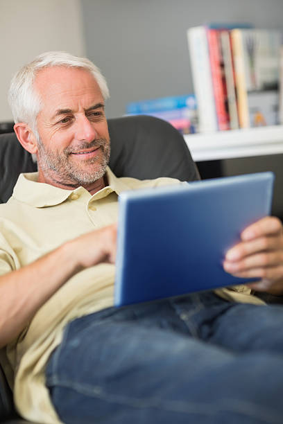 istock Mature man relaxing with his tablet pc and smiling 462617673